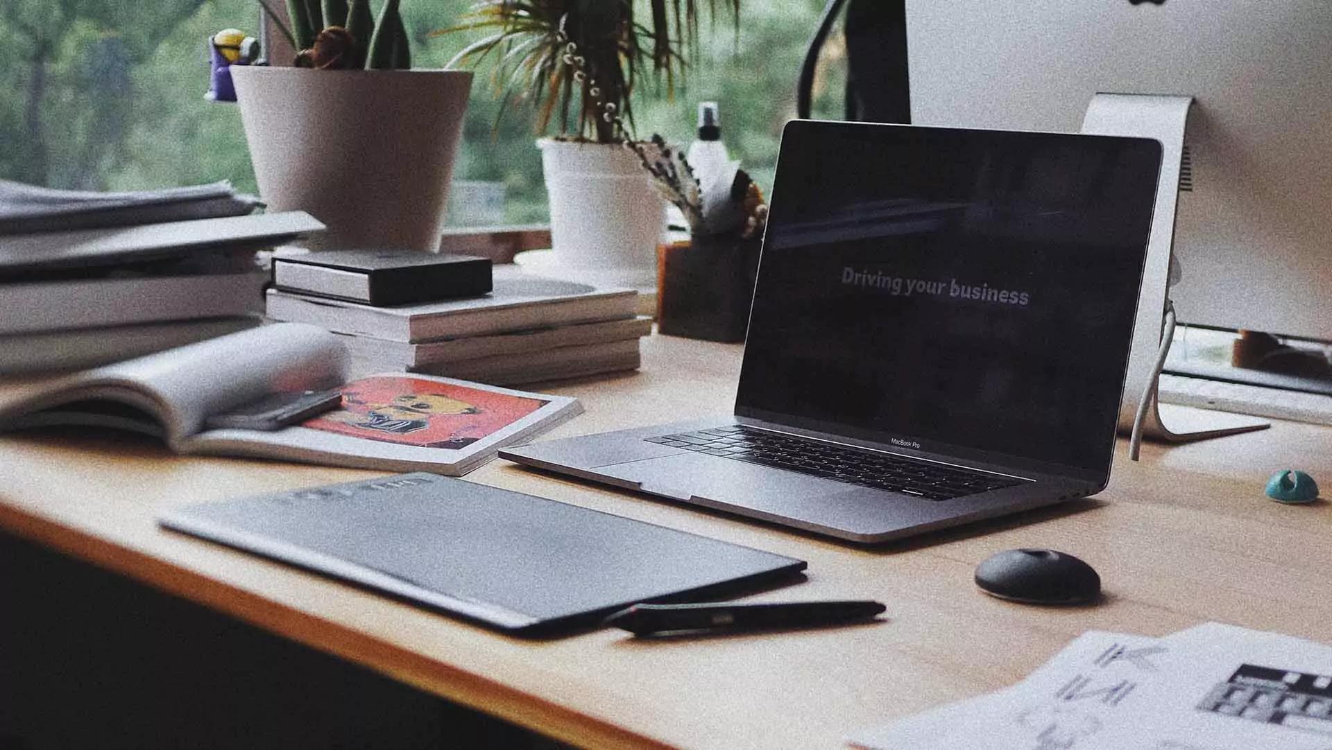 A notepad and laptop is on a desk